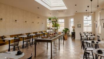 A spacious dining area with high ceilings, natural light from skylights, and a variety of seating options including tables and benches.
