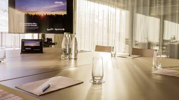 A conference room with a large flat-screen TV displaying a scenic image, a tablet, and several bottles of water on the table.