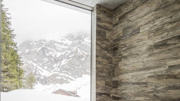 Un cuarto de spa con un amplio ventanal que ofrece vistas a montañas nevadas.