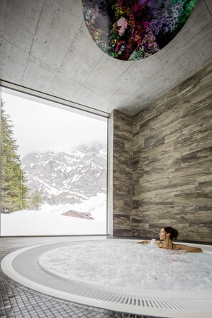 A spa room with a large window offering a view of snow-covered mountains. - Säntis - Das Hotel (Hundwil)
