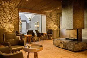 Un área de estar moderna con sofás de cuero, mesas de madera y una chimenea de piedra.