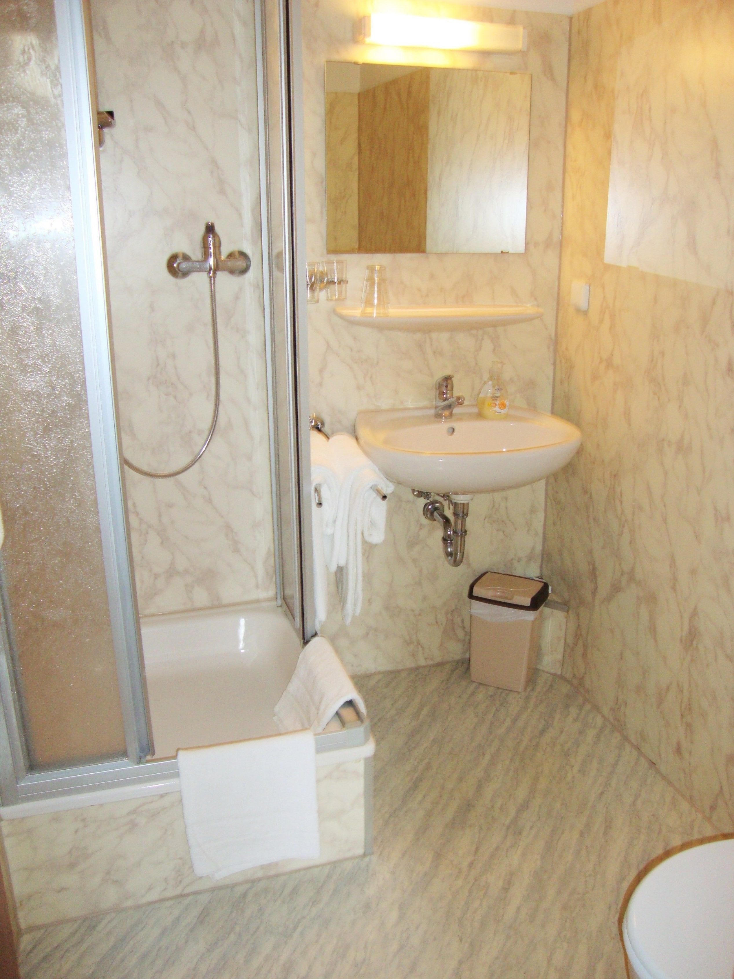 A bathroom with a shower, sink, and toilet.