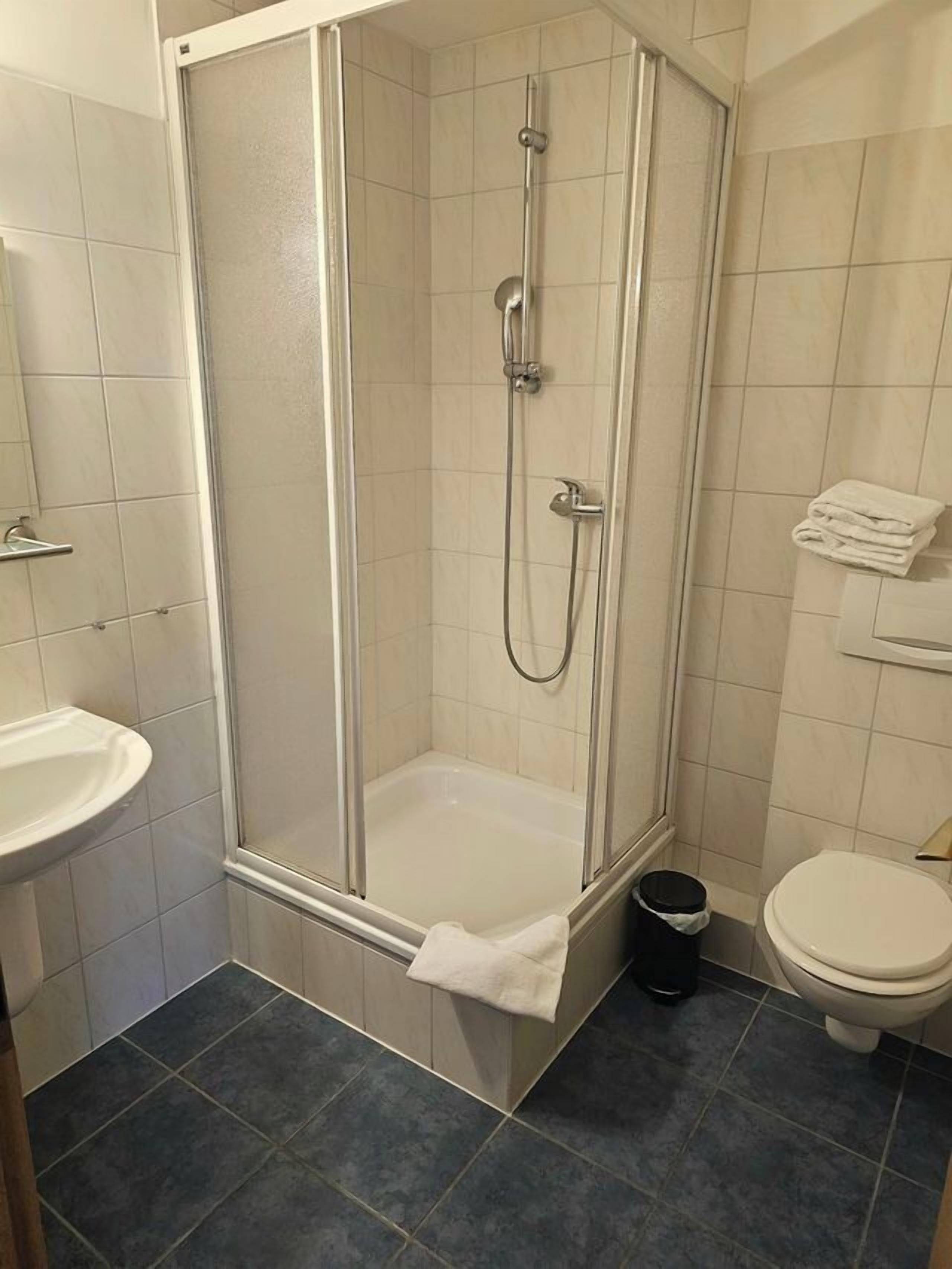 Een badkamer met een douche met glazen wand, een wastafel en een toilet.