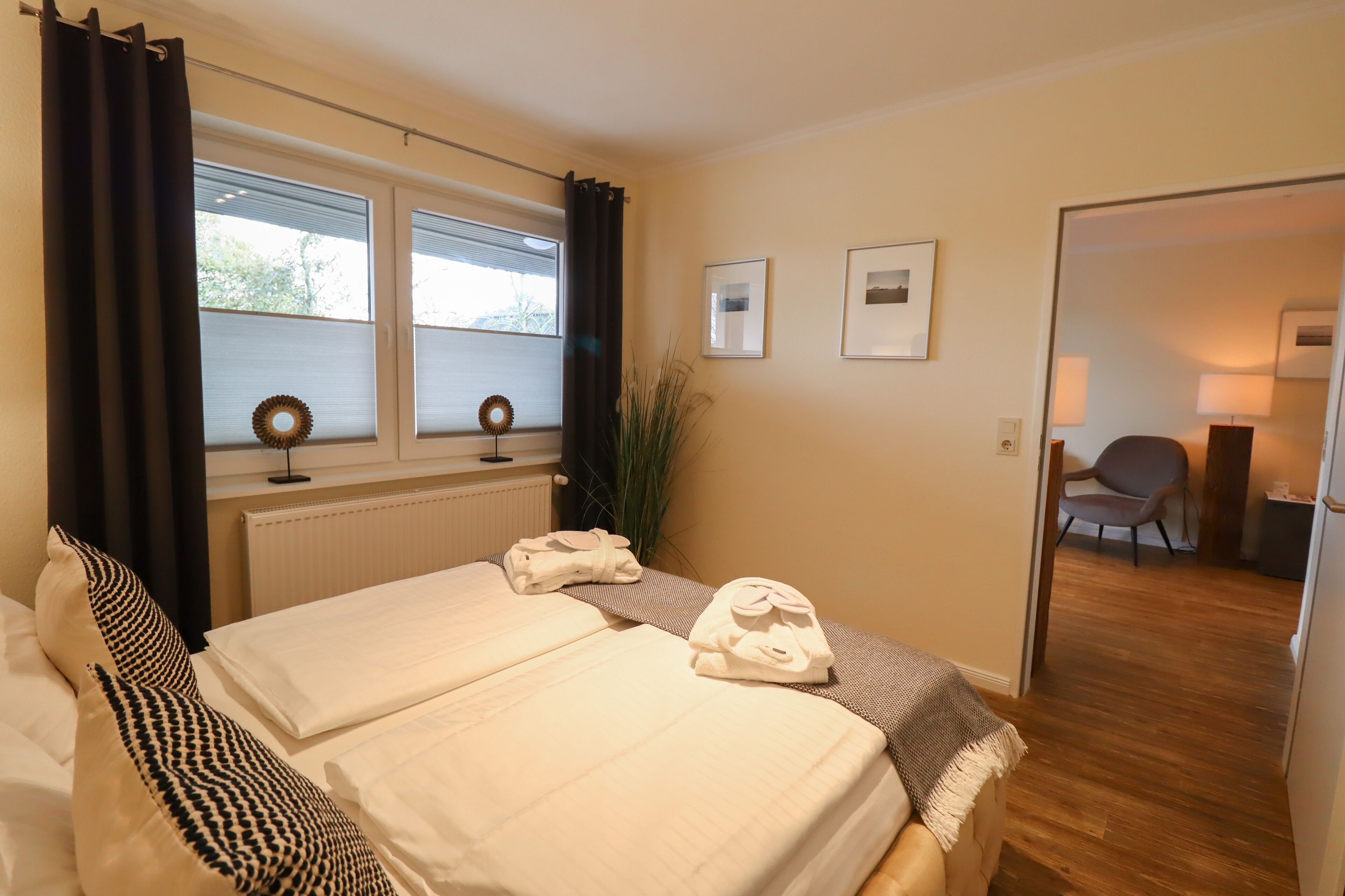 Habitación de hotel con dos camas, vistas al exterior, una silla y una lámpara.