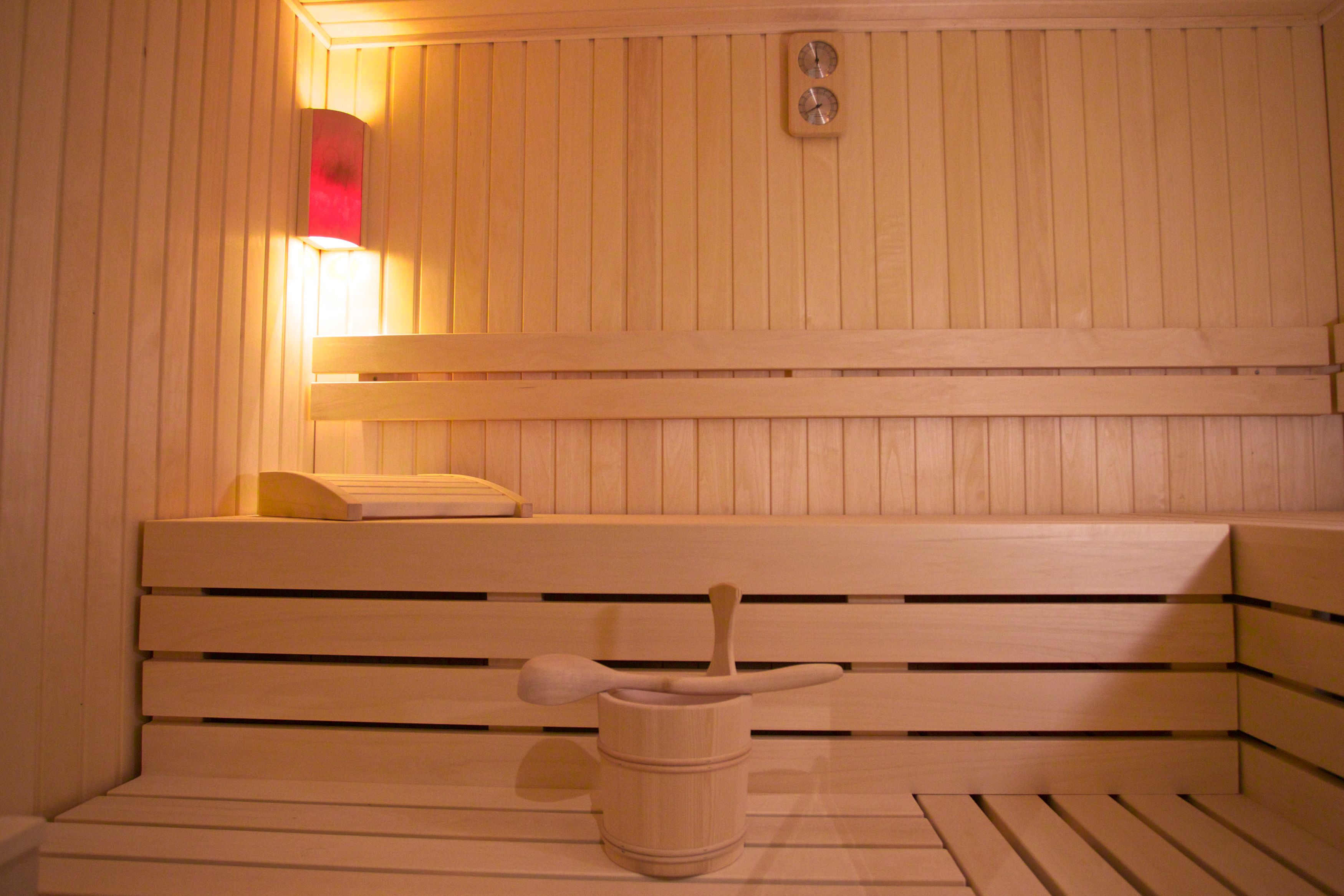 Eine Sauna mit Holzbänken und einem Holzfass mit Bürste.