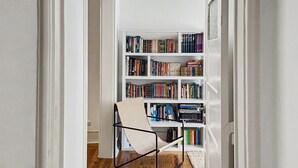 Un couloir menant à une pièce où se trouvent une bibliothèque, une chaise et un plancher en bois.