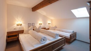 A room with two beds, wooden headboards, wall-mounted light fixtures, a skylight, and a small wooden shelf. - Hotel Bernhard am See (Walchsee)