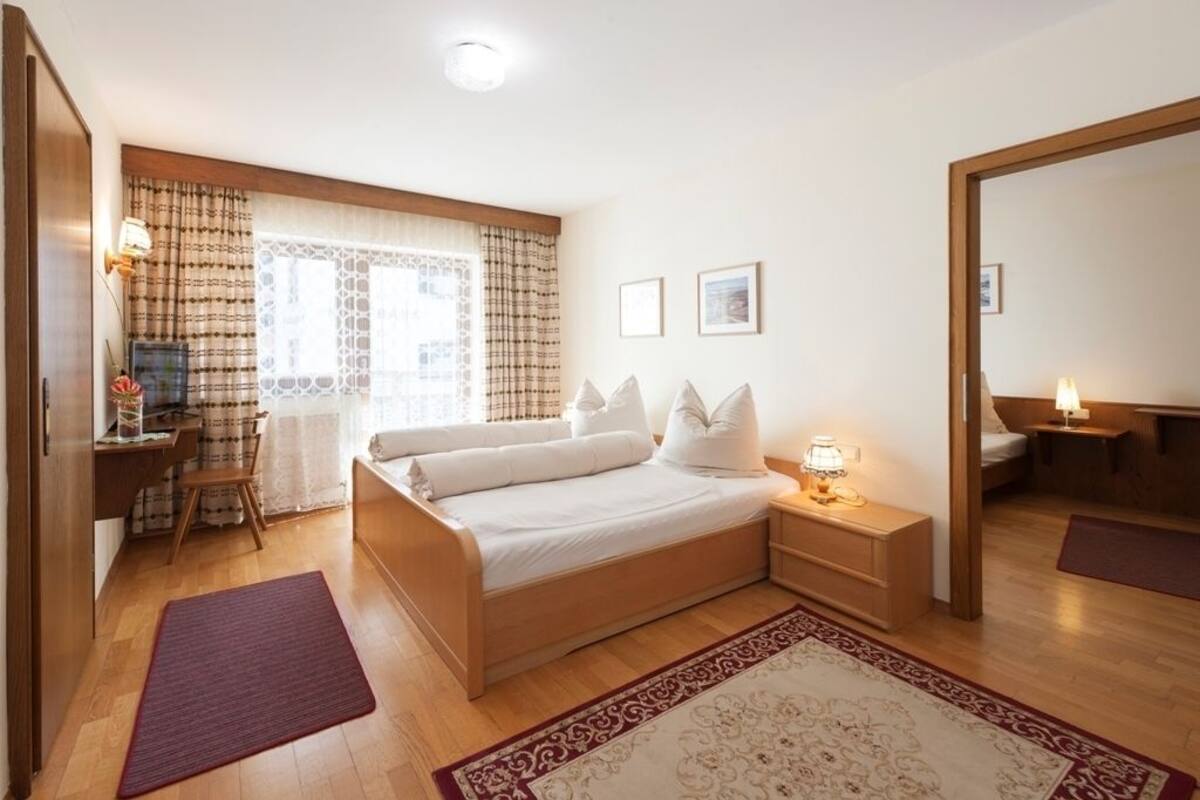 A bedroom with a bed, bedside tables, a desk, and a chair.