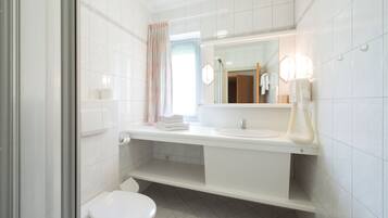 Ein modernes Badezimmer mit einem weißen Waschbecken, Spiegel und WC.