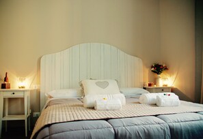 A neatly made bed with a striped headboard, two bedside tables with lamps, and a vase with flowers on the right side. - Tinkerbell Roma (Rome)