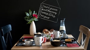 Une table de petit-déjeuner avec une cafetière, un pot à lait, des croissants et un vase rempli de fleurs.