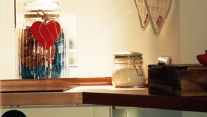 Une cuisine avec une fenêtre, une cloche suspendue, un pot à sucre et un luminaire fixé au mur.