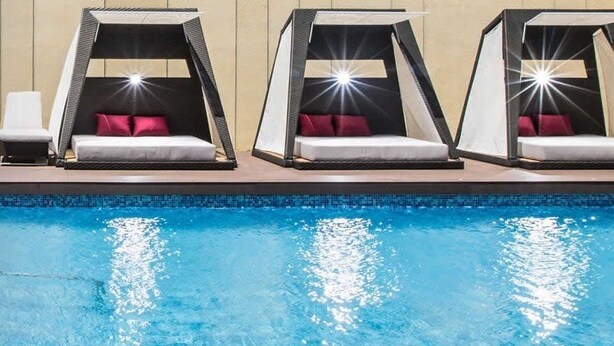 Un área junto a la piscina con tres tumbonas y una silla de descanso.