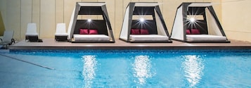 Un área junto a la piscina con tres tumbonas y una silla de descanso.