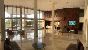 Un vestíbulo amplio con una zona de estar espaciosa, un mostrador de recepción y una pantalla de televisión.