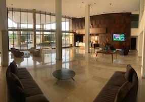 Un vestíbulo amplio con una zona de estar espaciosa, un mostrador de recepción y una pantalla de televisión.
