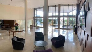 Un vestíbulo amplio con muebles modernos, ventanas grandes y un piso limpio y pulido.
