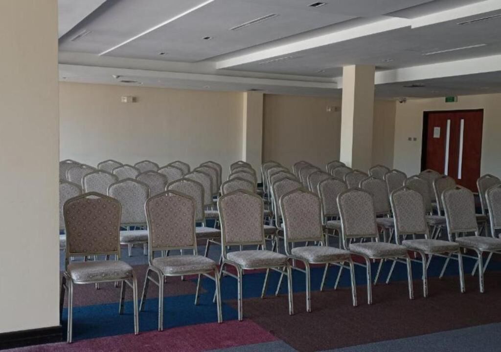 A conference room with rows of chairs and a carpeted floor.