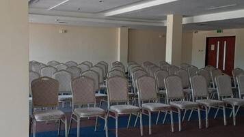 A conference room with rows of chairs and a carpeted floor.