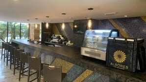 Zona de bar moderna con barra, asientos y una vitrina de comida.