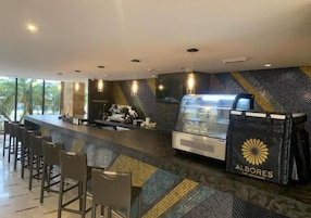 Zona de bar moderna con barra, asientos y una vitrina de comida.