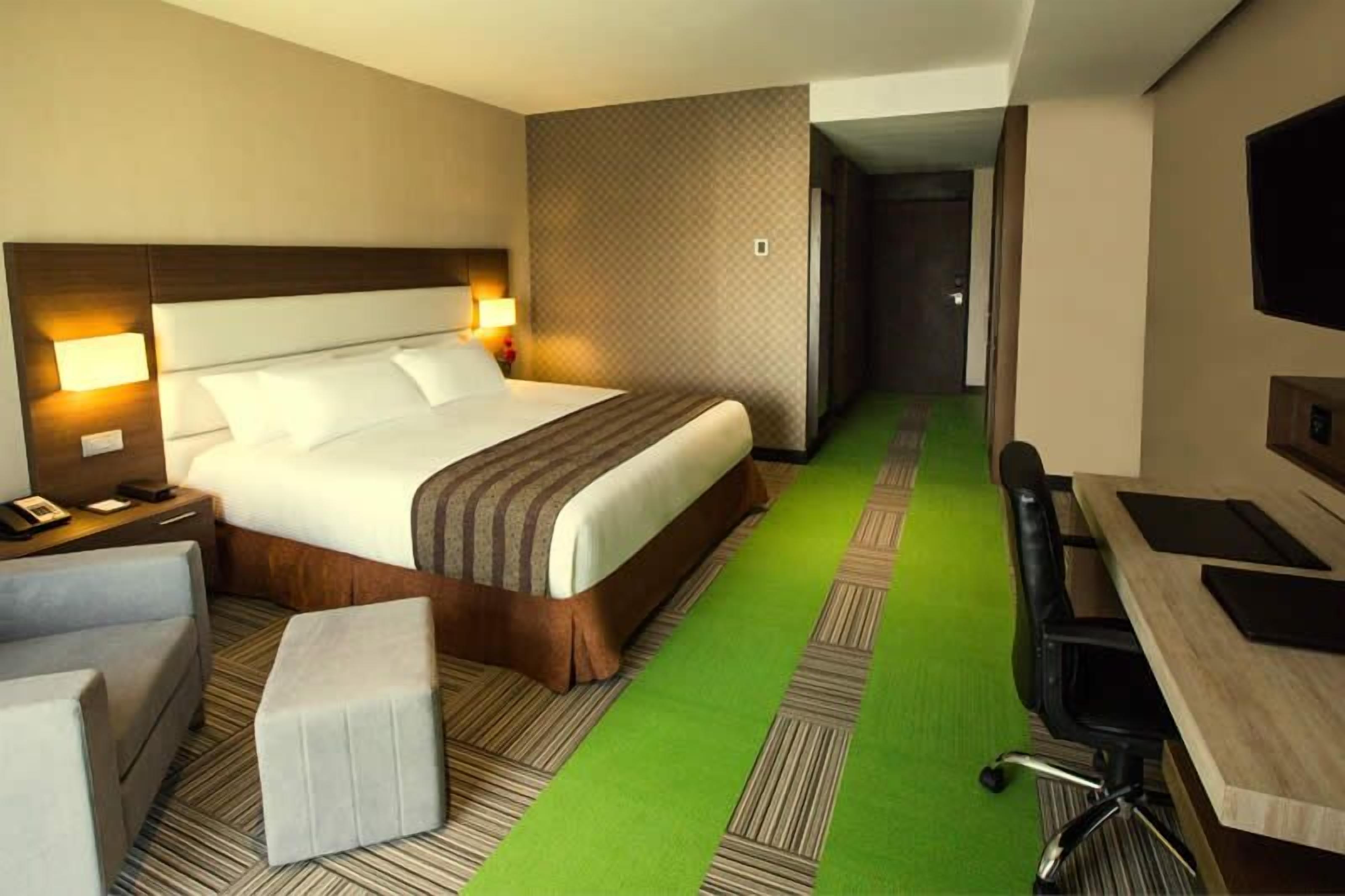 Una camera d'albergo con un letto grande, una scrivania, una sedia e una televisione.