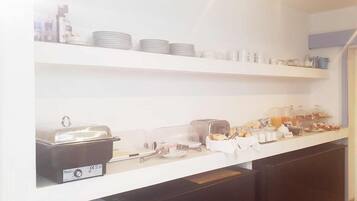 Montaje de bufé con diversos alimentos y utensilios sobre estantes blancos.