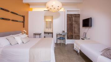 A hotel room with two beds, a desk, a chair, a television, and a bathroom visible through an open door.