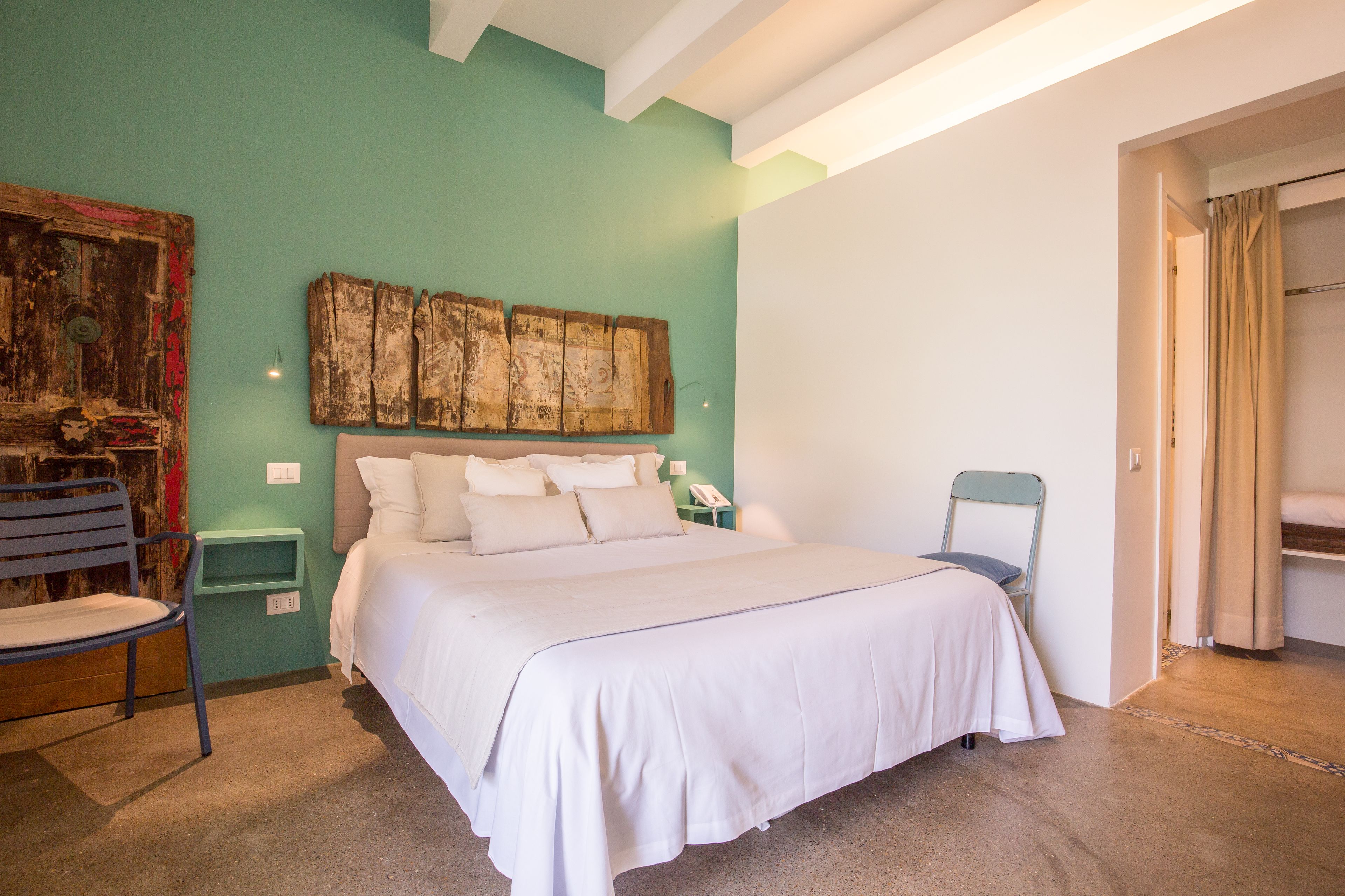 A bedroom with a bed, a chair, a nightstand, and a wall art piece.