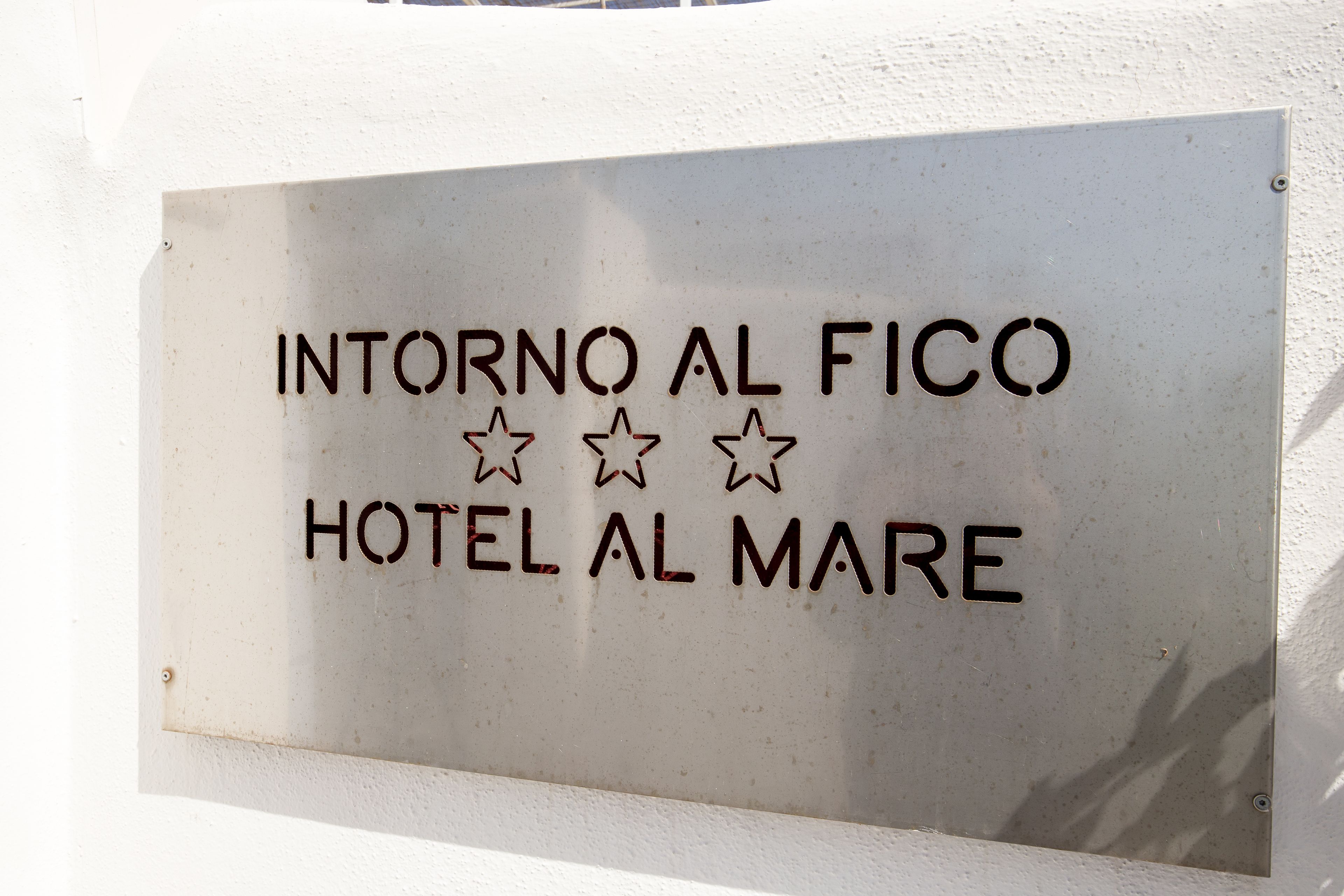A sign for "INTORNO AL FICO HOTEL AL MARE" with three stars.