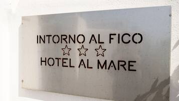 A sign for "INTORNO AL FICO HOTEL AL MARE" with three stars.