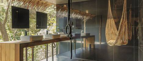A modern bathroom with a wooden vanity, a large mirror, and a hanging hammock.