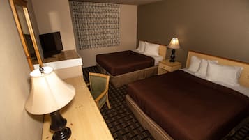 Une chambre d’hôtel avec deux lits, un bureau avec une lampe, une chaise, un téléviseur et une décoration murale à motifs.