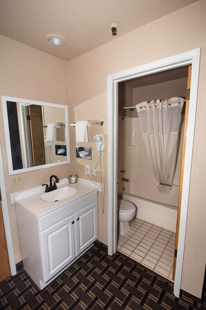 A bathroom with a white sink, mirror, and toilet. There is a shower curtain and a towel rack.