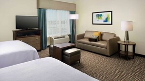 A hotel room with two beds, a sofa, a TV, and a window with curtains.