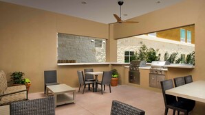An outdoor patio with wicker furniture, a stone wall, and a view of the garden.