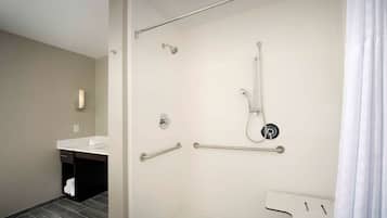 A modern bathroom with a shower, grab bars, a towel rack, and a sink.