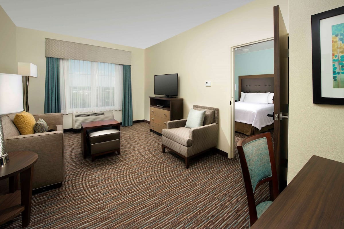 Une chambre d’hôtel comprenant un lit, une télévision, un canapé, une chaise, un bureau et un sol recouvert de moquette.