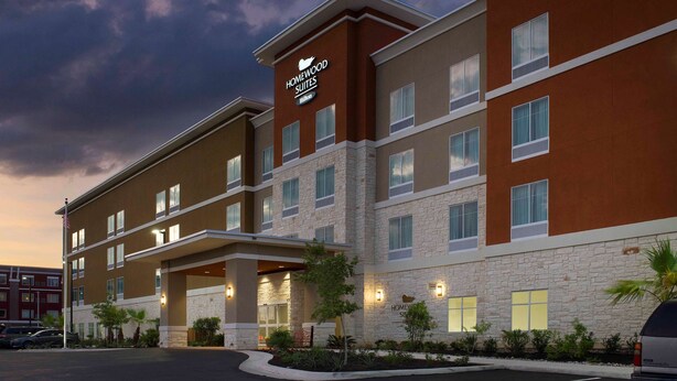 A multi-story hotel with a stone facade, multiple windows, and a sign indicating it is a Homewood Suites Hilton.