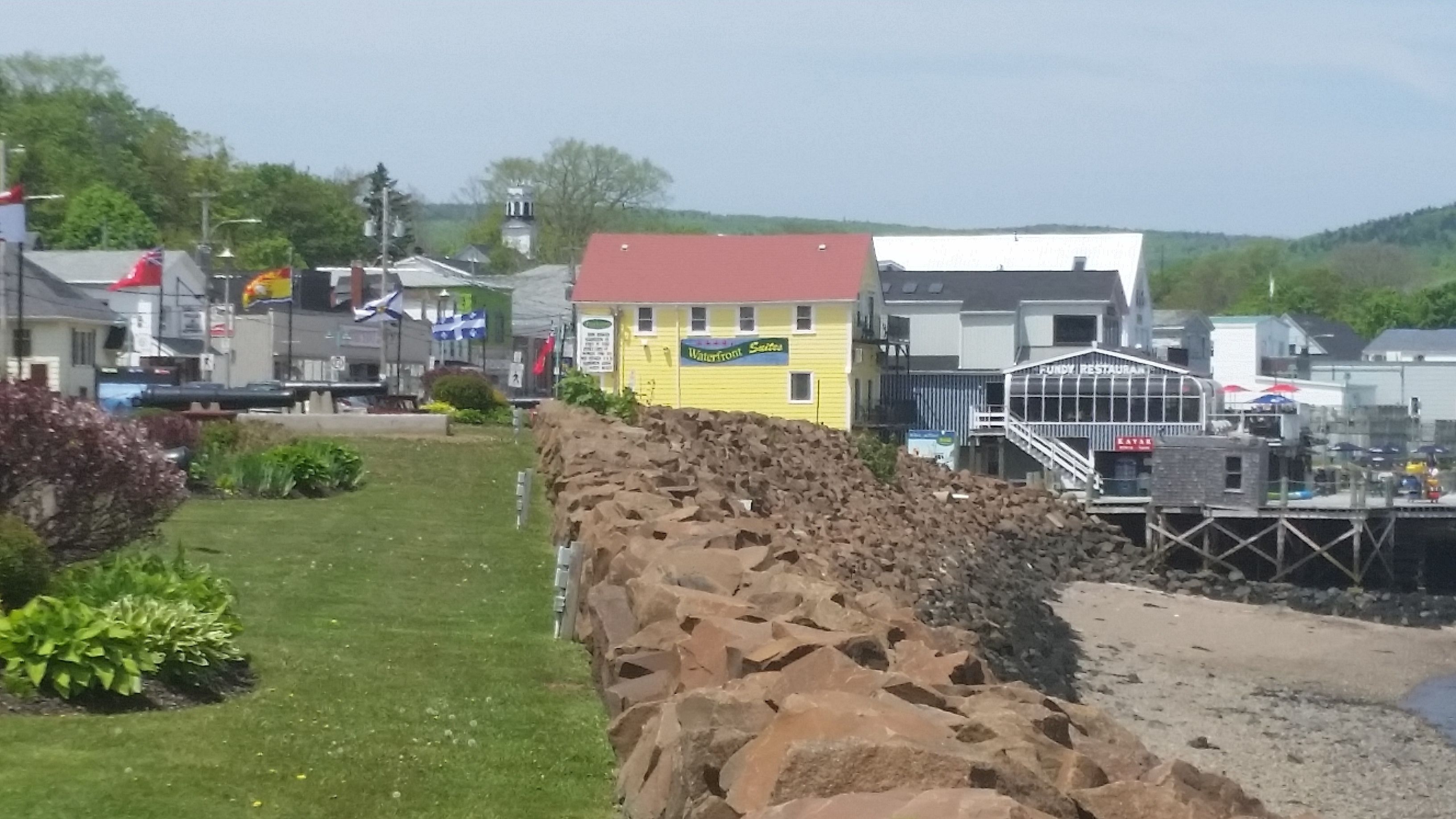 A waterfront building with a red roof, a sign for 'Waterfront Suites', and a restaurant named 'Fundy Restaurant'.