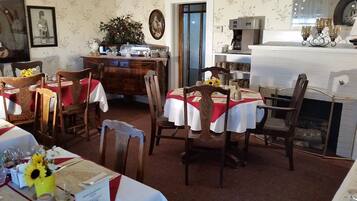 Zona pranzo con sedie e tavoli in legno, una macchina per il caffè e un camino.