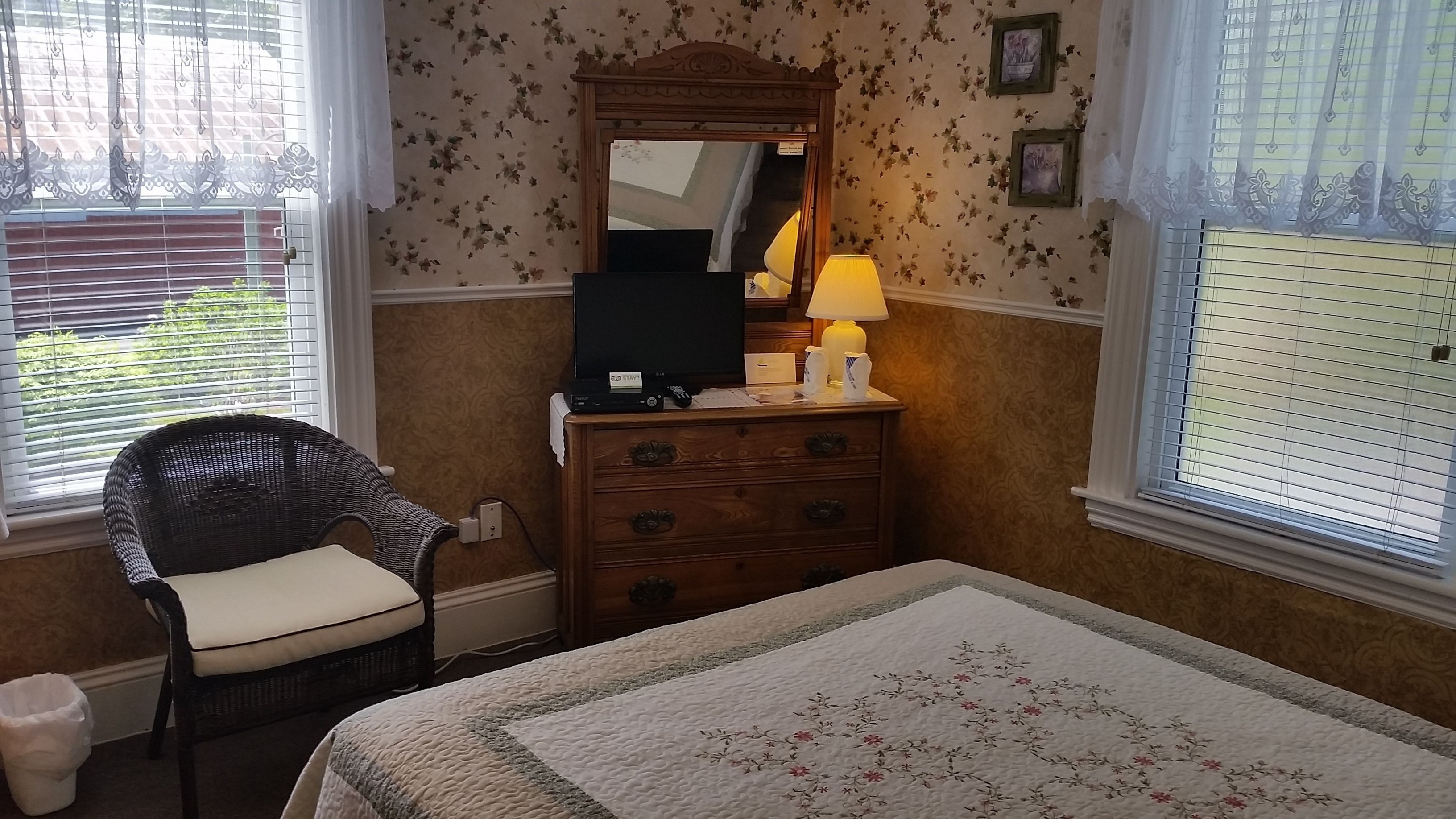Une chambre à coucher avec un lit, une commode, une chaise et un miroir.