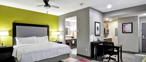 Una habitación de hotel con una cama grande, un escritorio, una silla y un banco rojo.