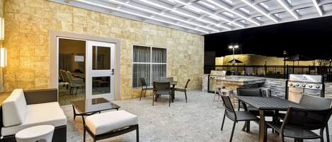 An outdoor patio with a stone wall, a grill, and seating.