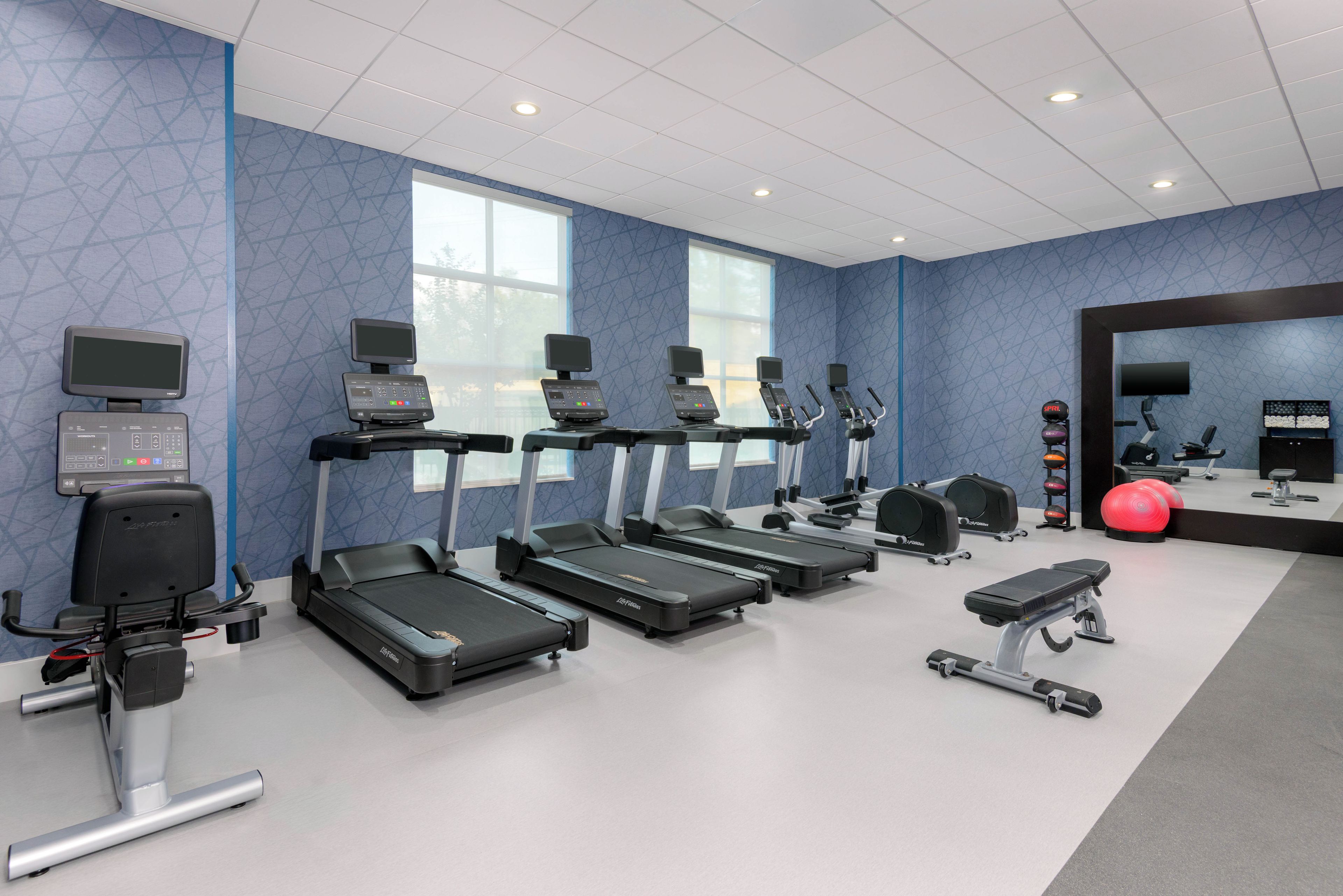 A gym with treadmills, exercise bikes, and a rowing machine.