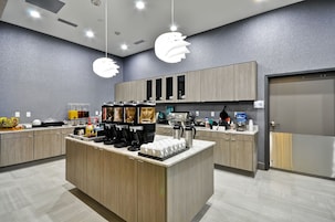 Una cocina moderna con una isla central, electrodomésticos integrados y una estación para café.