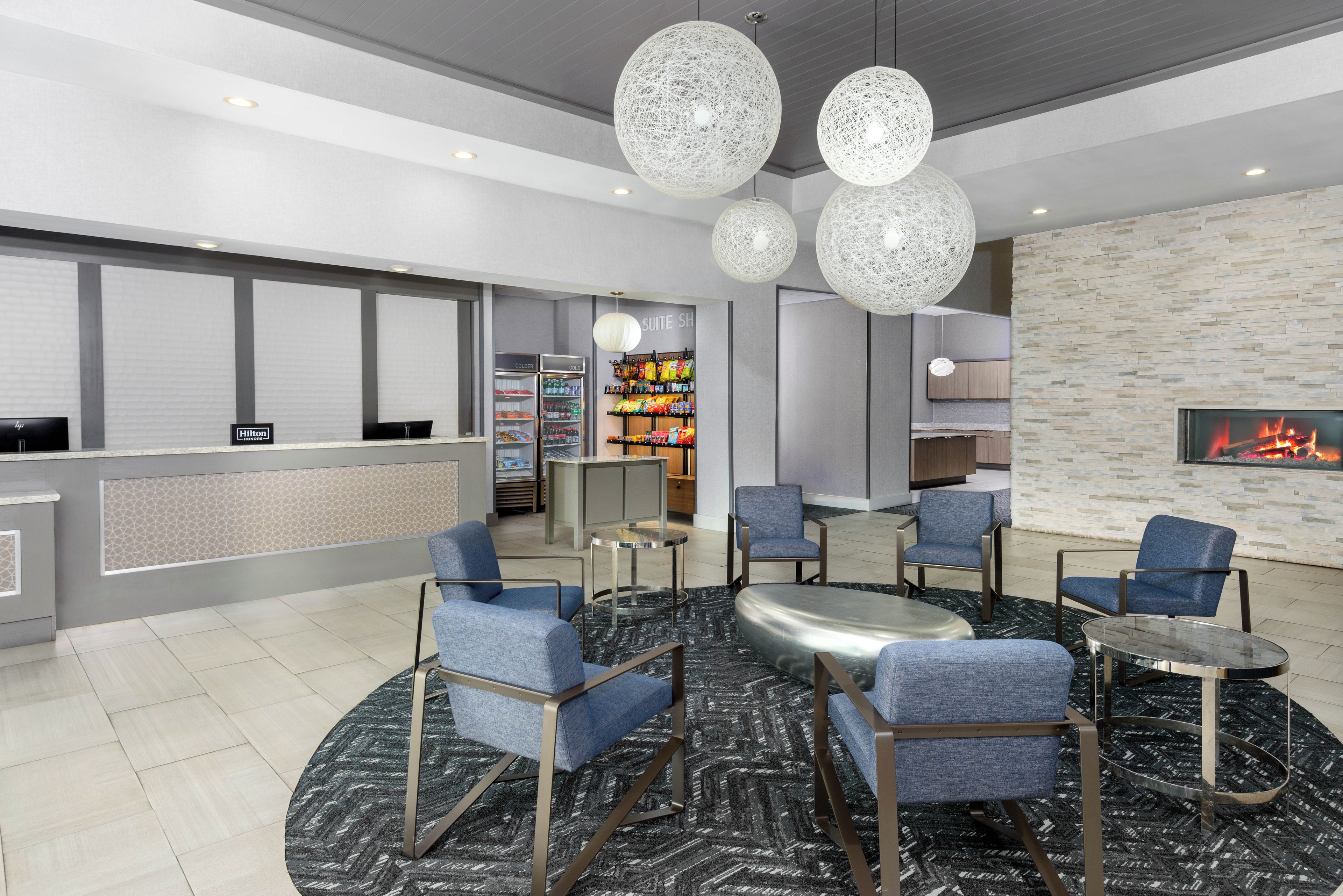 A hotel lobby with seating, a reception desk, a minibar, and a fireplace.