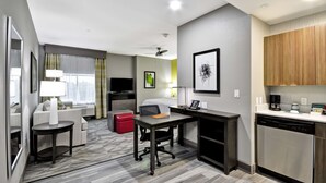 A compact hotel room with a kitchenette, a dining area, a sofa, a small table, and a red ottoman. - Homewood Suites by Hilton Tyler (Tyler)
