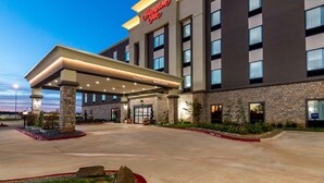 A Hampton Inn hotel with a modern facade, a covered entrance, and a landscaped front area.