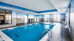 An indoor swimming pool with clear signage, a lifeguard chair, and a seating area with chairs.